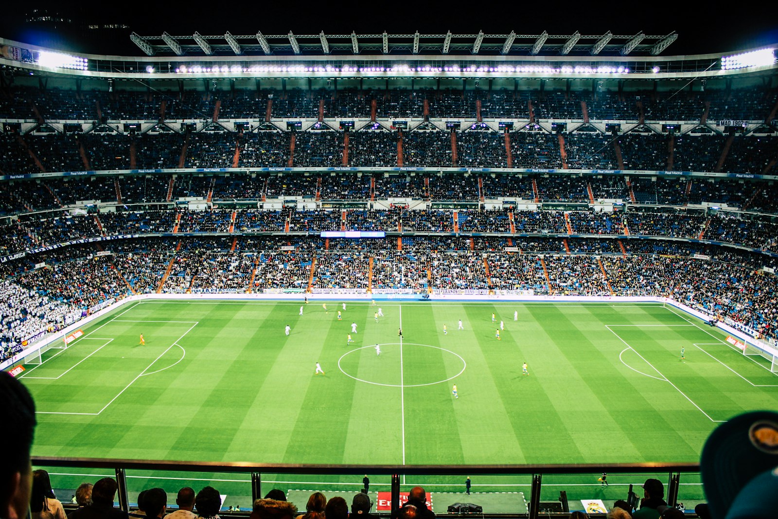 Bancadas cheias num estádio de futebol durante um jogo à noite