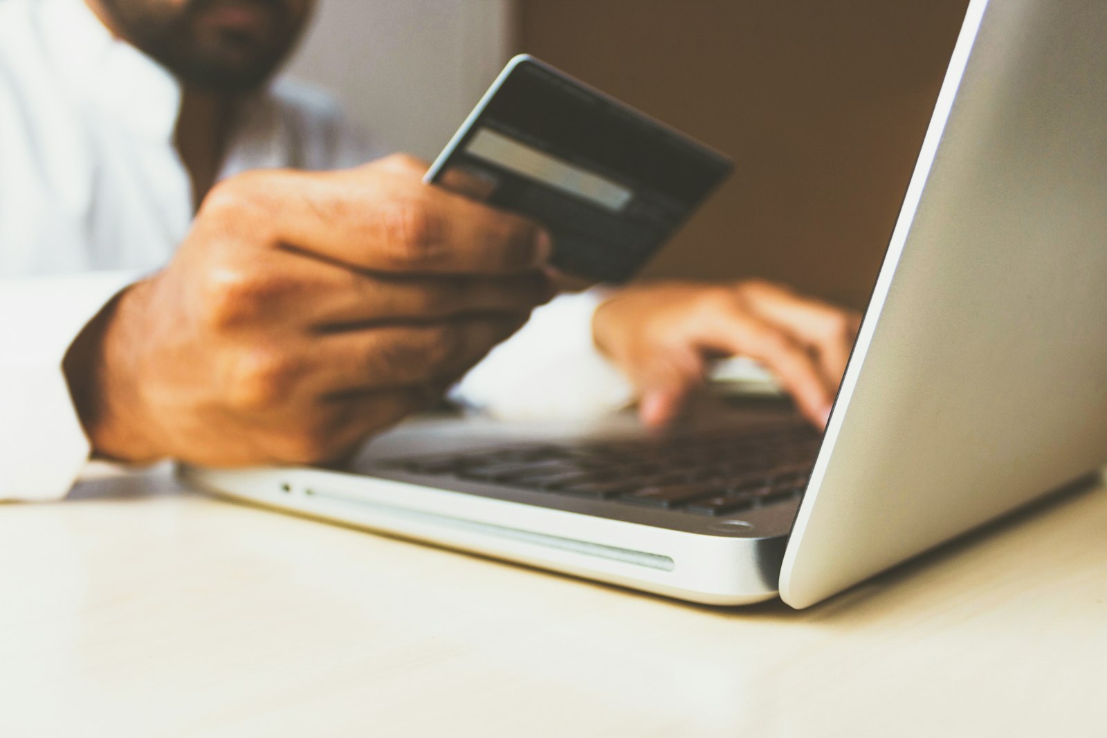 Pessoa a pagar uma compra online com cartão à frente de um portátil